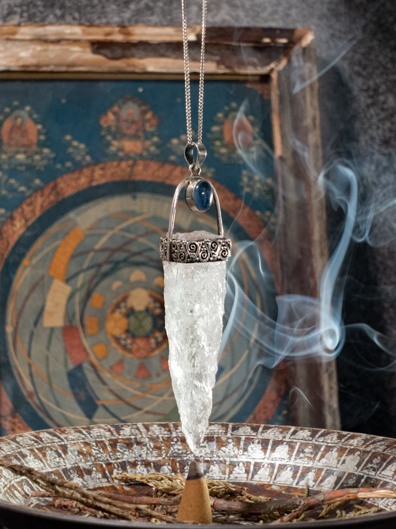 Crystal pendant on a chain over an incense burner with smoke