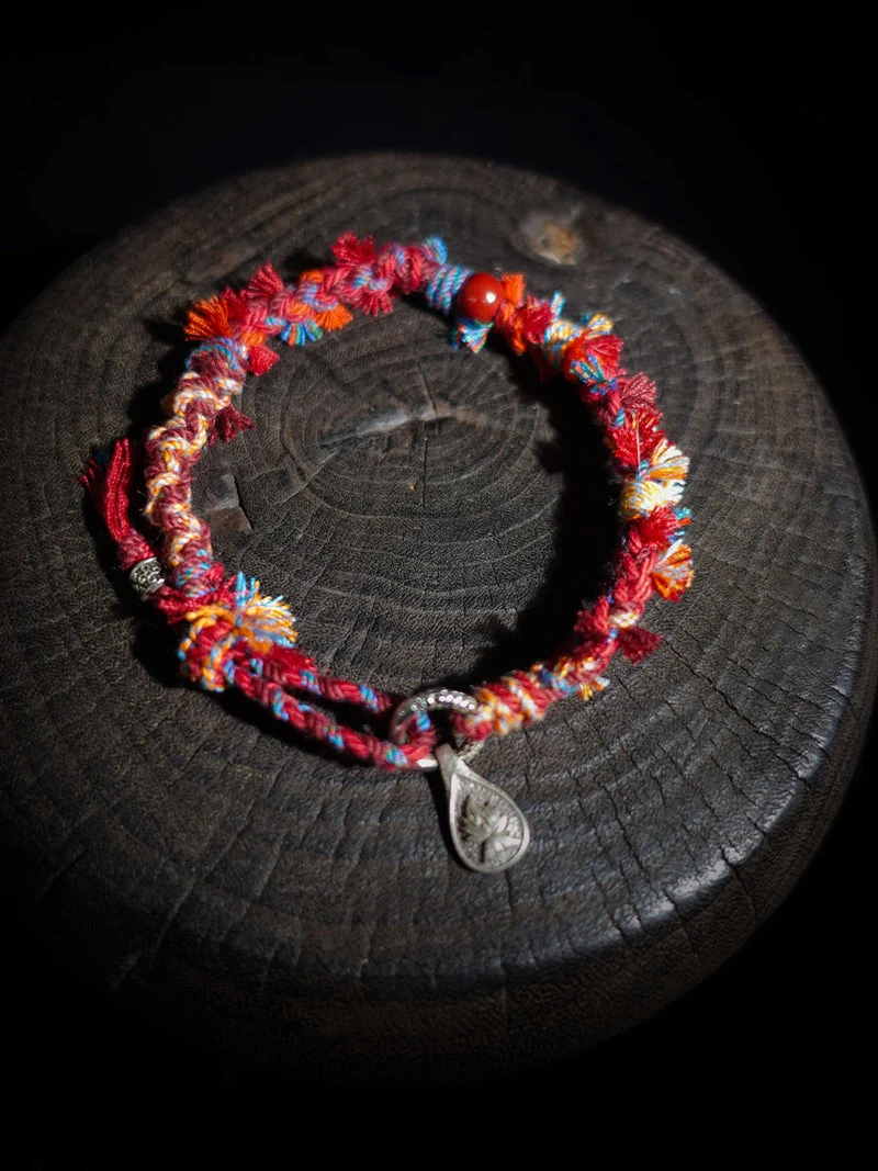 Colorful beaded bracelet with a silver charm on a dark surface