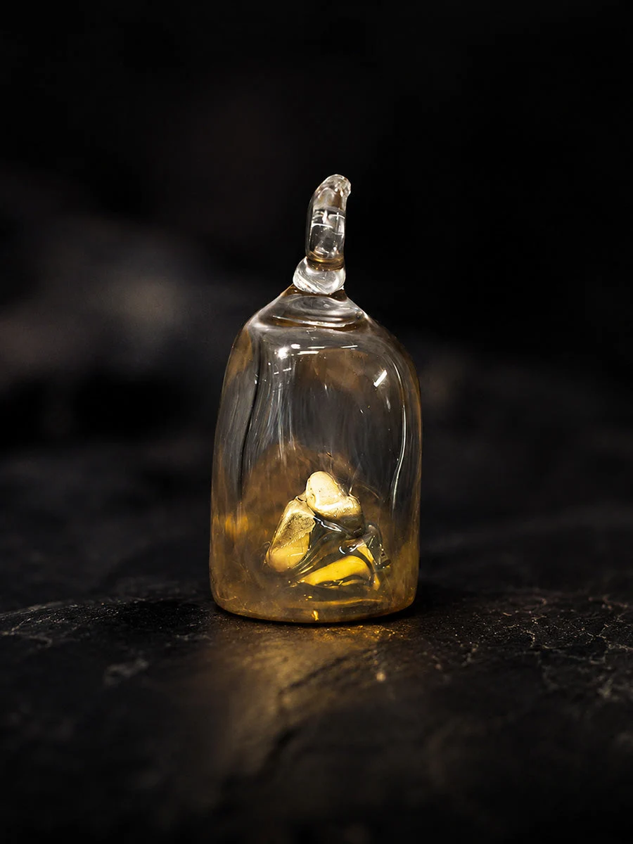 Small glass bottle with a stopper containing a small figurine on a dark surface